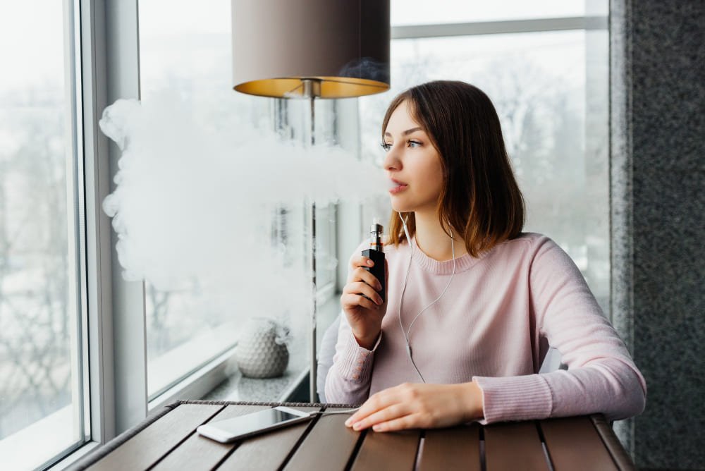 une femme fume une cigarette électronique