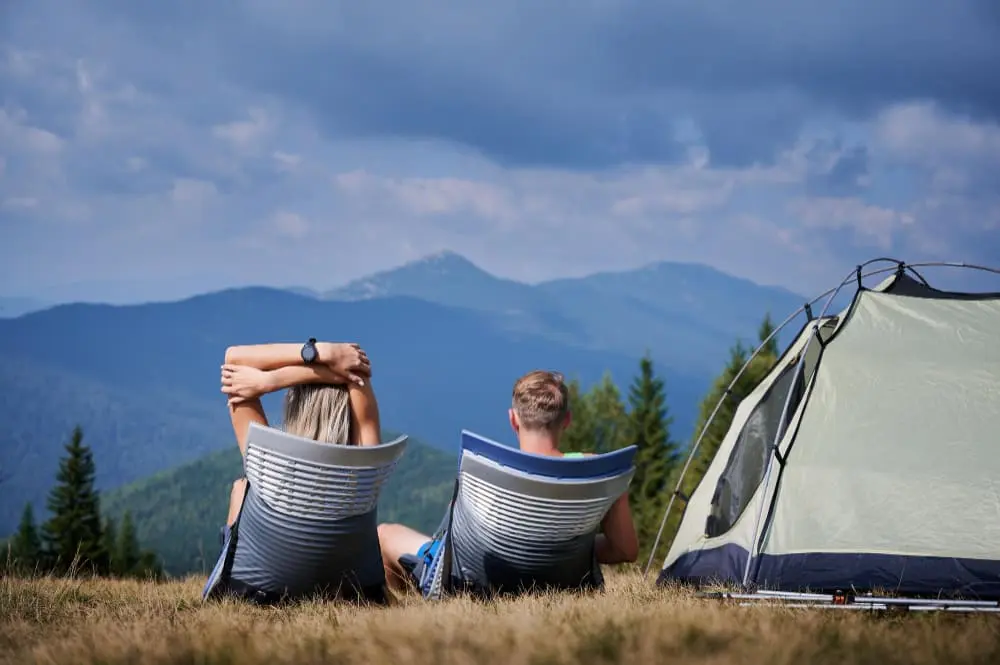 Couple installé en camping face aux collines et montagnes verdoyantes